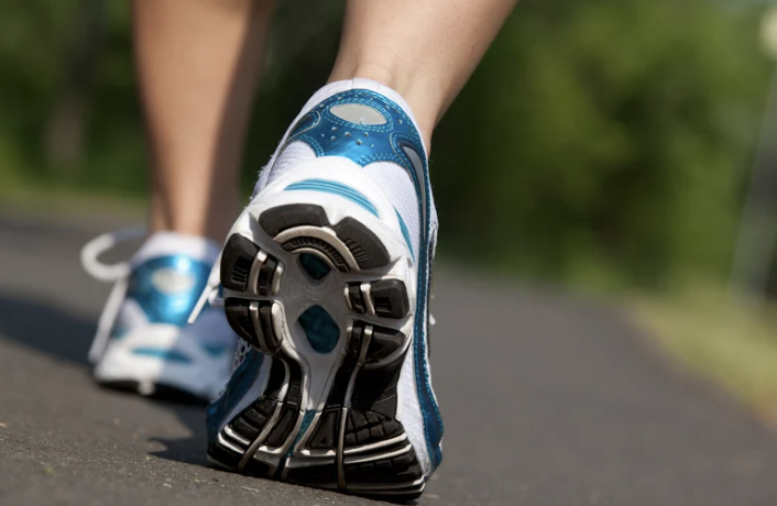 A woman's feet walking on a paved road.