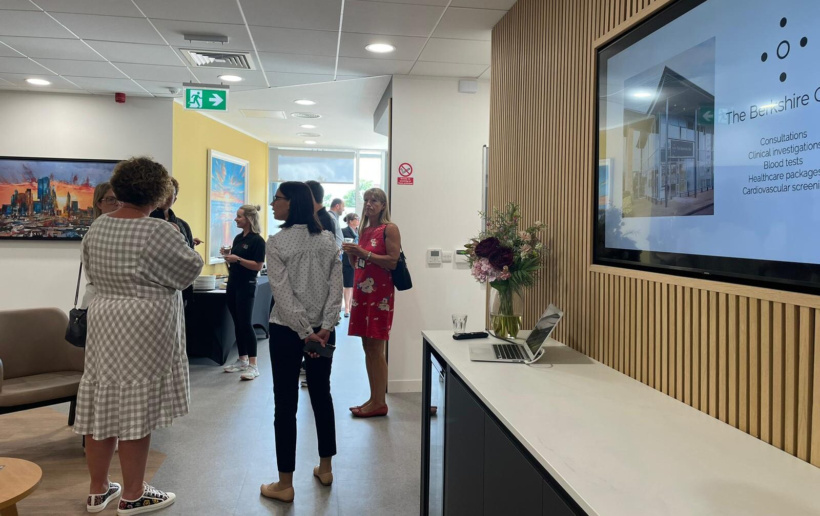 A group of people standing in front of a tv in an office.