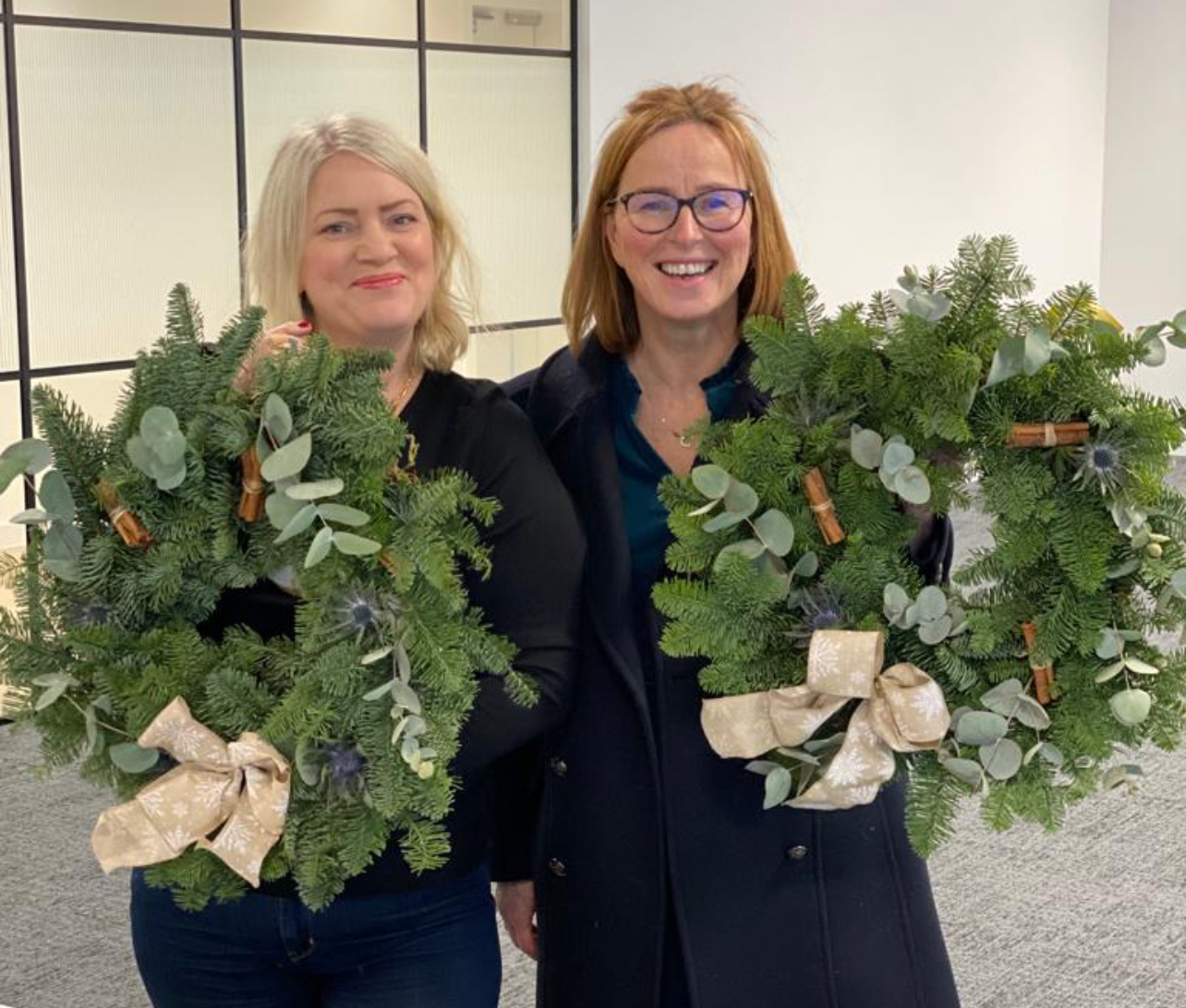 Two women holding wreaths in front of one another.